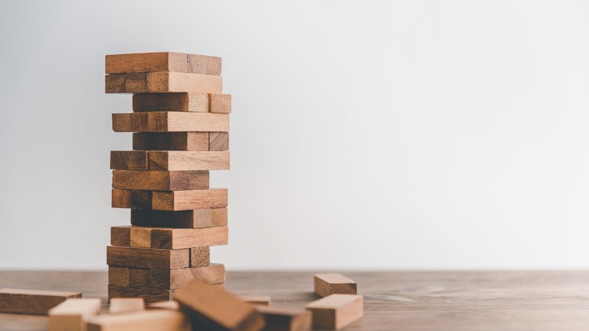 Torre di blocchi di legno con spazi vuoti tra gli elementi e altri pezzi sparsi sul tavolo.