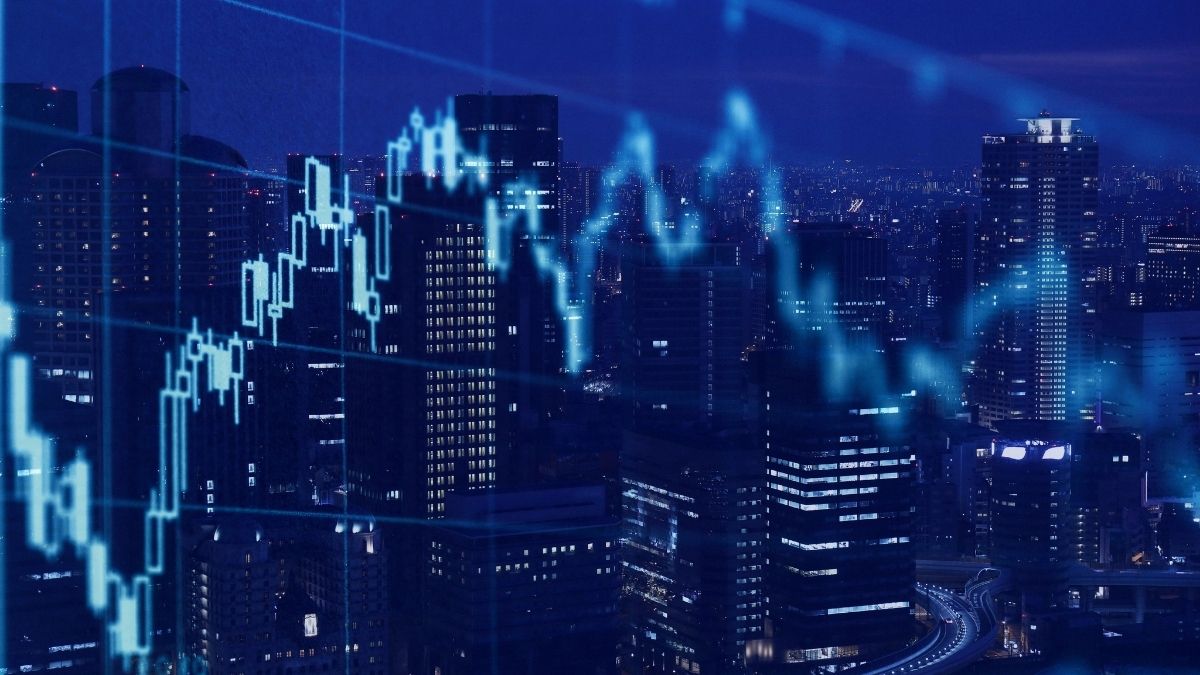 Grafico finanziario luminoso sovrapposto a edifici alti e illuminati di una città di notte, in tonalità blu.